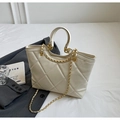 Detail of quilted beige tote bag with gold chain strap and elegant urban styling props - One Size / Off White