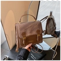 Détail macro du sac à dos rétro en cuir bicolore avec boucle dorée et logo poli - Marron