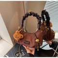 Dettaglio borsa a tracolla marrone vintage in camoscio con manico in pelle e ciondolo orsetto - caffè