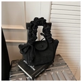 Close-up of black suede handbag featuring a pleated scrunchie handle and bow detail - Black