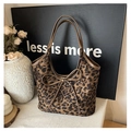 Close-up of leopard print tote bag with leather bow accent and long shoulder straps - Brown