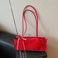 Red suede shoulder bag with decorative bows and plush ball on a black book surface - With Charm / Red