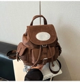 Close-up of brown suede backpack featuring silver oval nika logo and front pocket details - Brown