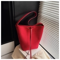 Primer plano del bolso cubo de ante rojo con cordón de cuero sobre libros de arte - Rojo