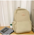 Detail des hellbeige Laptop-Rucksacks mit Lederlogo-Patch und vorderer Reißverschlusstasche - Khaki