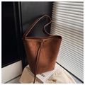Detail of soft brown suede bucket bag texture and leather strap on vintage art books - Brown