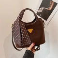 Sac seau marron avec logo doré et foulard à pois sur fond blanc minimaliste - Marron