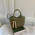Detail der grün geflochtenen Handtasche mit Holzperlen und wellenförmigem Design - Grün