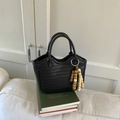 Detail einer schwarzen geflochtenen Halbmond-Handtasche mit Perlen-Quaste auf Büchern - Schwarz
