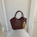 Detail der weinroten geflochtenen Handtasche mit Holzperlenquaste und welligem Rand - Braun