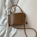 Brown woven drawstring bucket bag with handle and metal feet shown in lifestyle view - Brown