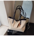 Detail view of cream canvas tote bag featuring brown leather handles and wooden bead charm - Off White