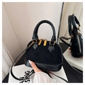 Close-up of black shell-shaped crossbody bag with gold hardware and mirror reflection - Black