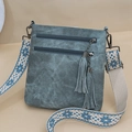 Detail view of a vintage crossbody bag with dual tassel zippers and embroidered strap - Blue