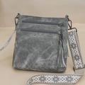 Detail view of grey crossbody bag featuring multi-zipper layers and embroidered wide strap - Gray