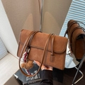 Minimalist brown suede shoulder bag featuring a plush bear charm and striped scarf accent - Brown