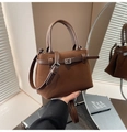 Close-up of matte dark brown bucket bag featuring fine waist belt buckle and dual handles - Brown