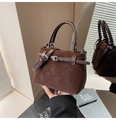 Detailed close-up of dark brown suede bucket bag featuring polished leather strap and metal buckle - Brown