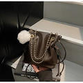 Detail of dark brown drawstring bucket bag with gold chain strap and plush ball - Coffee