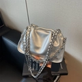 Silver metallic pleated shoulder bag with chain strap on a designer book background - Silver