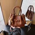 Dark brown woven leather bucket bag with top handles and a vintage bead charm detail - Brown with Pendant