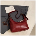 Detalle de bolso medialuna de cuero burdeos con colgante de perro sobre traje - Rojo con Colgante