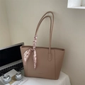 Brown leather tote bag with lychee texture and pink houndstooth scarf on white table - Apricot
