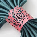 Close-up of coral red laser-cut rose napkin ring on a dark green satin cloth - Pearlescent Red
