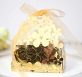 Macro shot of laser-cut floral patterns on golden gift box with organza ribbon - Reflective Gold