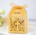 Détail macro du motif de croix découpé au laser sur boîte à bonbons dorée avec ruban - Or