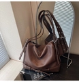 Gros plan sur la texture du cuir grainé marron foncé et les détails de boucle de ce sac - Marron