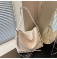 Vue détaillée du cuir blanc texturé et de la sangle à œillets argentés sur le sac hobo - Blanc