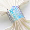 Detailed macro view of laser-cut iridescent metal napkin ring with rose flower pattern - Mirror Iridescent