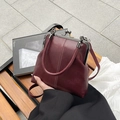 Nahaufnahme der burgunderroten Retro-Tasche mit Kontrastnähten und Metallverschluss - Rot