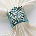Macro shot of teal hollow-out rose napkin ring on a white satin cloth for table decor - Mirror Indigo