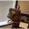 Detail eines braunen Vintage-Rucksacks mit goldener Metallplatte und weicher Ledertextur - Braun