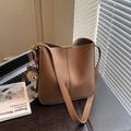 Brown litchi grain bucket bag with wide strap and plush pendant in office setting - Brown