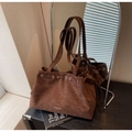 Detail of dark brown suede tote bag featuring drawstring closure and branded base stamp - Coffee