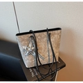 Detail of printed tote bag with silver star charm resting on a book in a modern setting - With Charm / Black