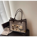 Detail of striped canvas tote bag with plush bear embroidery and laptop in a lifestyle setting - Brown