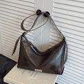Dark brown glossy leather hobo bag with adjustable strap on white art book base - Brown