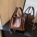 Bolso cubo retro marrón oscuro con logo HOGOMU y asa ancha mostrado en vista lateral - Marrón