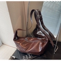 Detail of dark brown leather hobo bag featuring silver grommets on the wide shoulder strap - Brown
