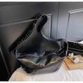 Detail of black leather crescent bag with diagonal stitching on a minimalist desk - Black