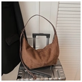 Detail of caramel suede hobo bag with adjustable leather strap on a travel suitcase - Brown