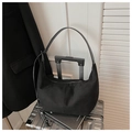 Detailed close-up of a black suede crescent hobo bag in a minimalist business setting - Black