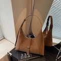 Dark brown suede hobo underarm bag with minimalist buckle detail on a book display - Brown