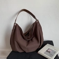 Detailed close-up of dark brown canvas tote bag with leather strap and metal hardware - Brown