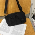 Black nylon utility crossbody bag with adjustable wide strap on a wooden chair - Black