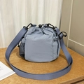 Blue nylon bucket crossbody bag with mesh pocket and drawstring closure on wood table - Blue